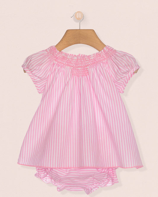 Pink and white striped baby dress on a hanger against a beige background