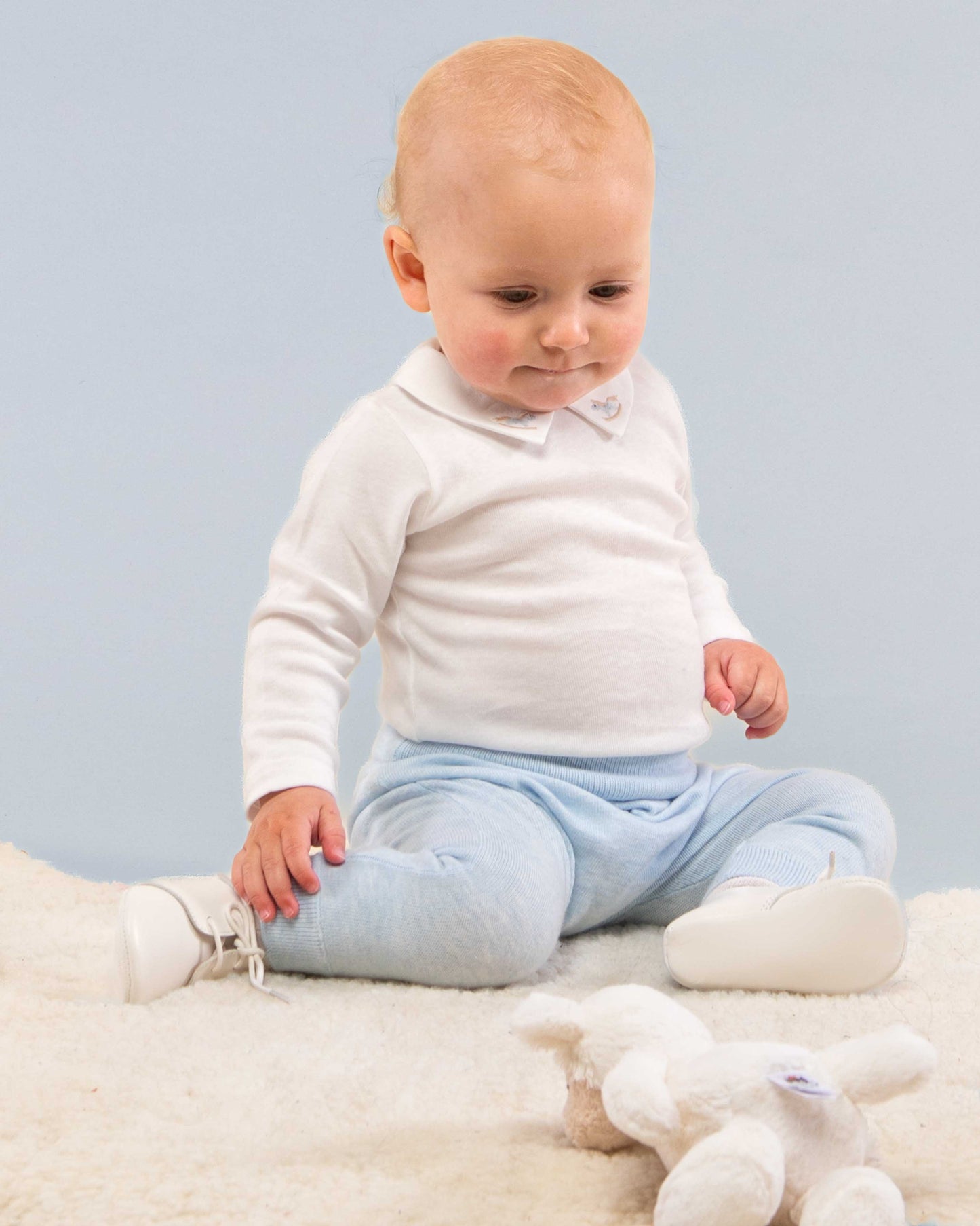 Baby sitting on the floor, wearing Jackpot Light Blue pant looking to the floor, showing the comfortability of the pants