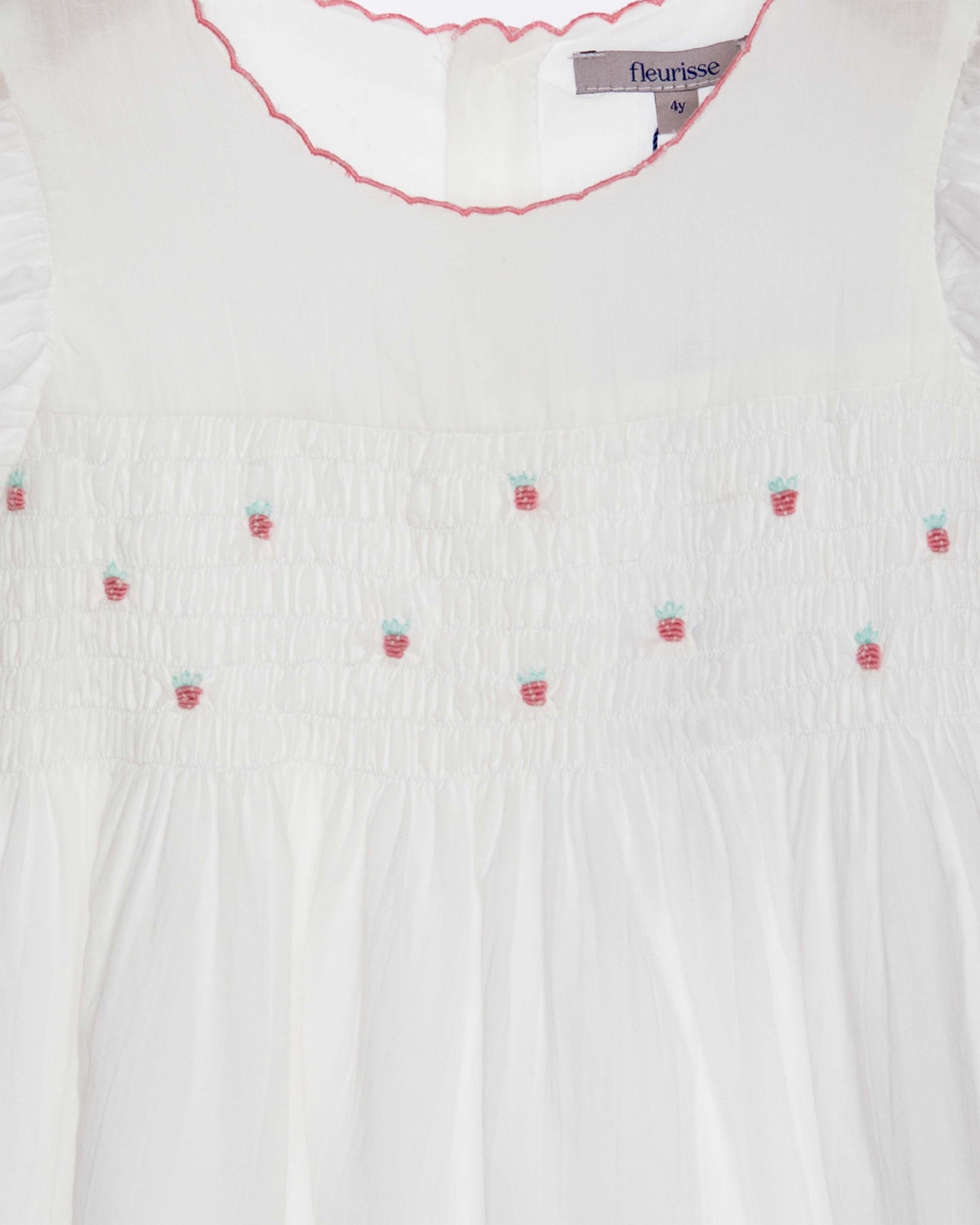 White blouse with strawberry embroidery and 'fleurisse' label.