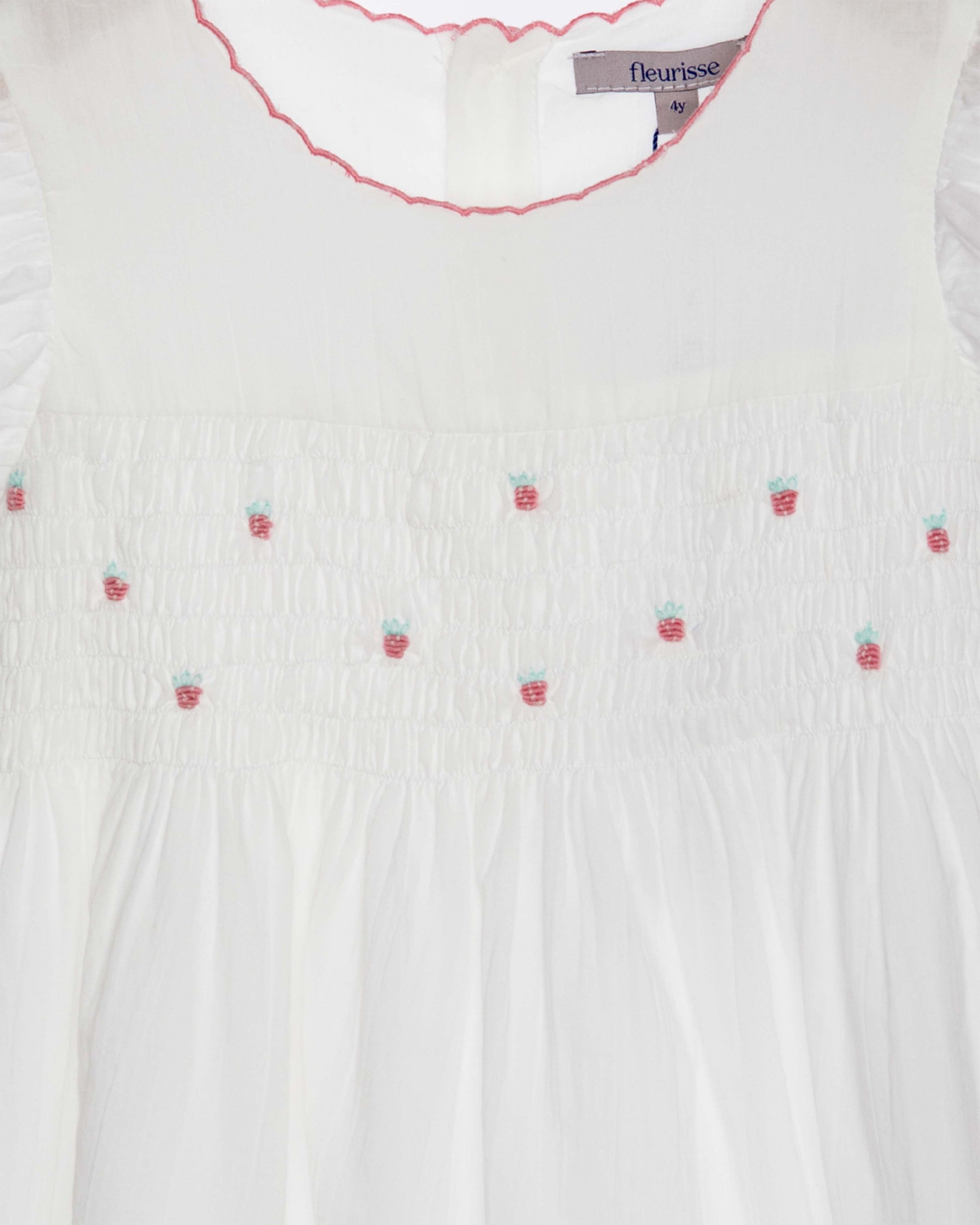 White blouse with strawberry embroidery and 'fleurisse' label.