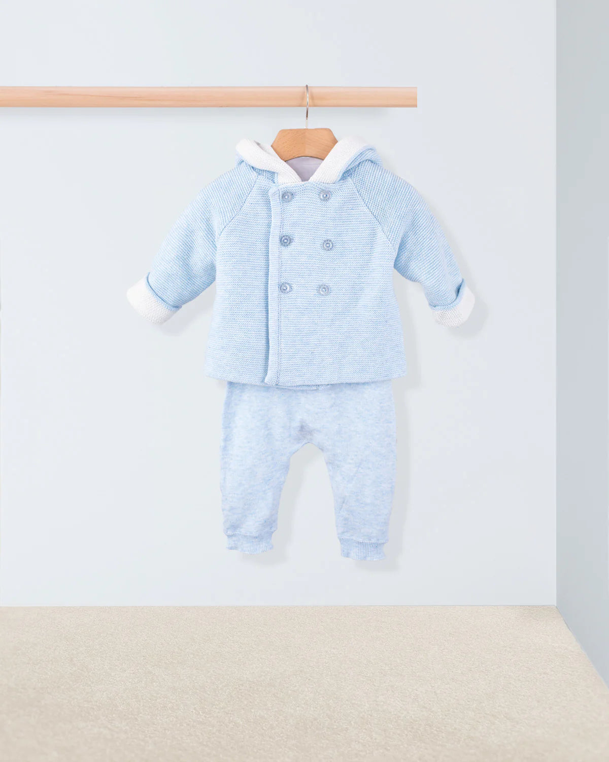 Light blue baby outfit with matching jacket and pants on a hanger against a light gray background.