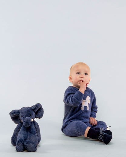 Baby boy model wearing the Logan Jean Cashmere Romper sitting down, showing the front of the romper