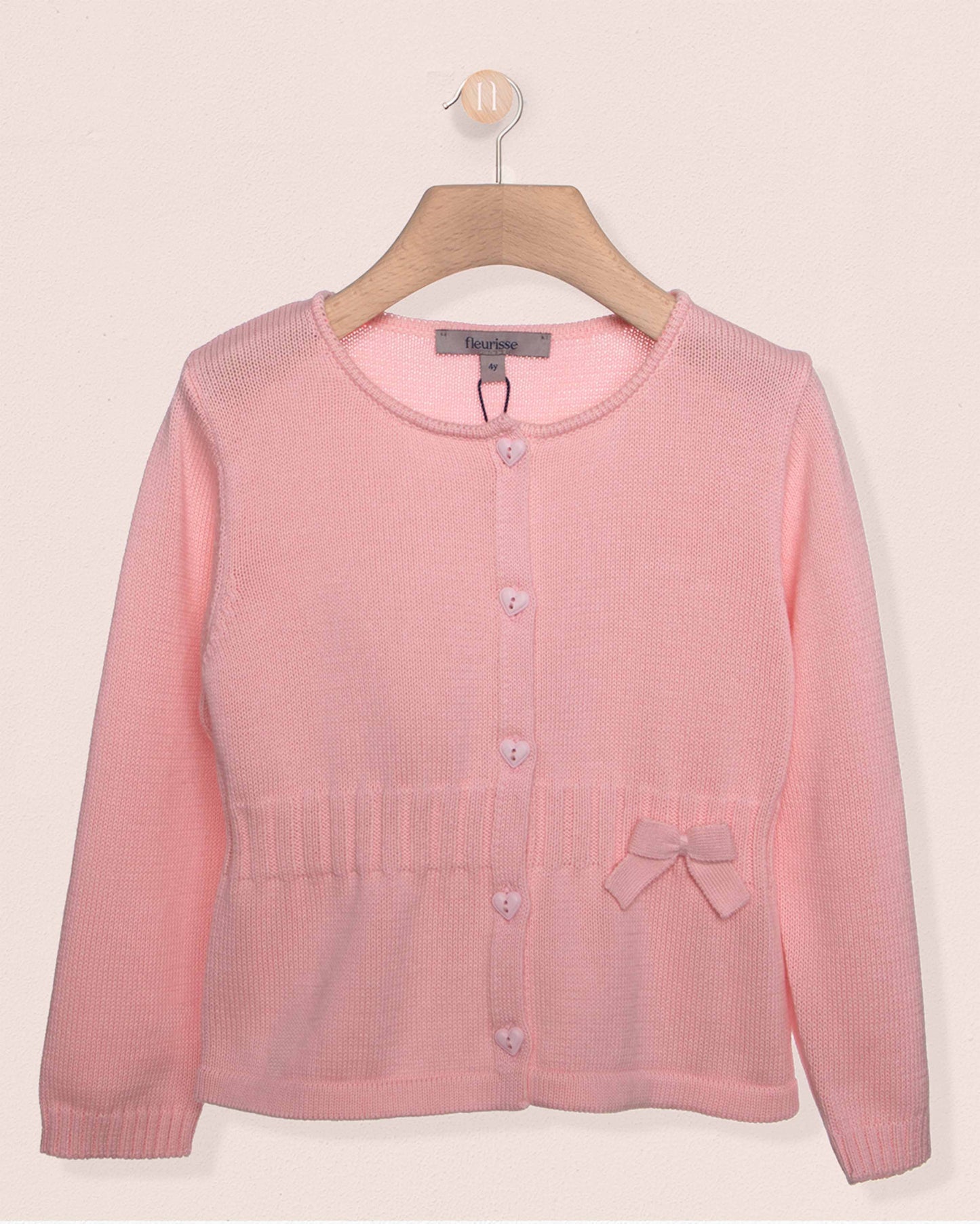 Pink cardigan on a hanger against a light pink background