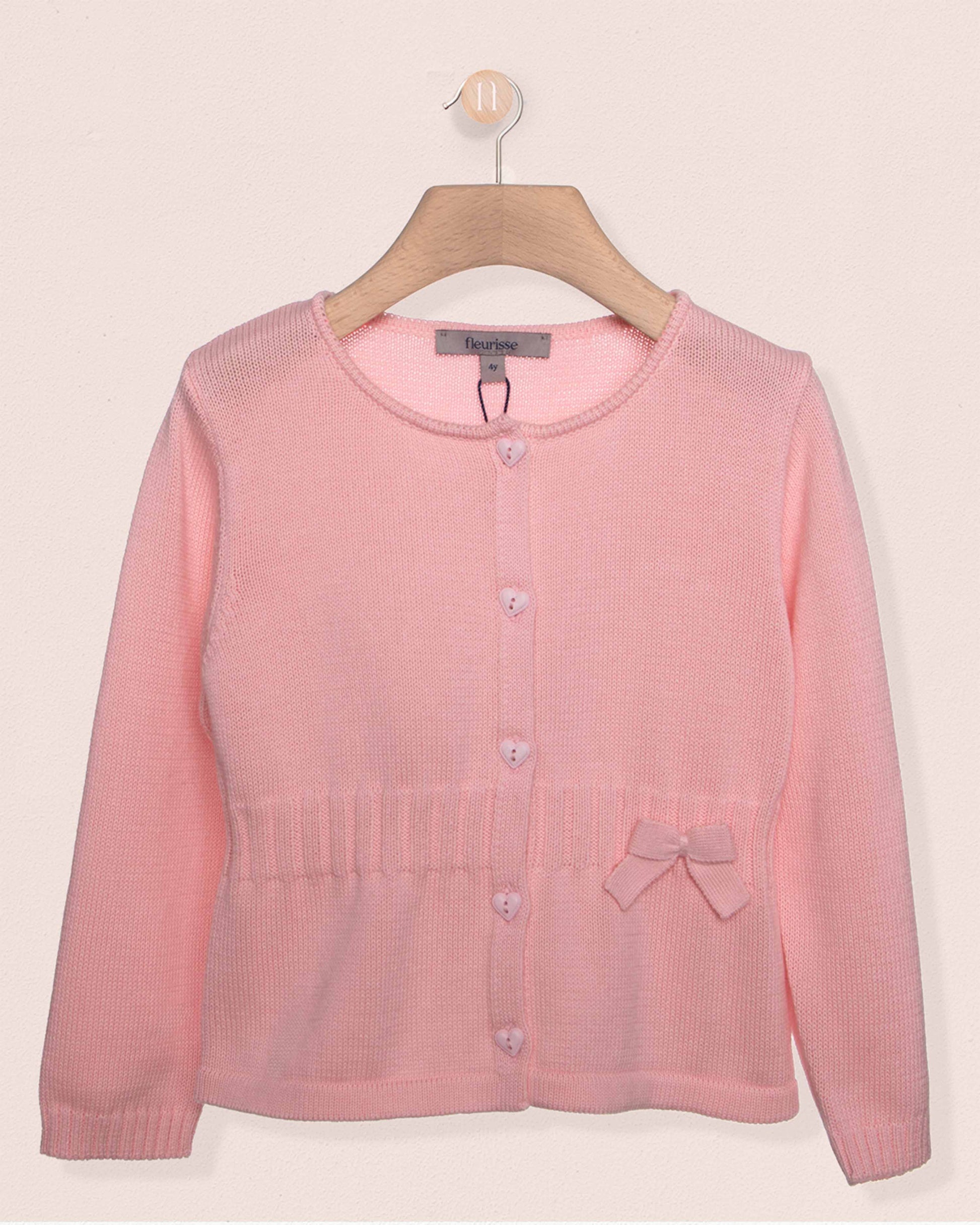Pink cardigan on a hanger against a light pink background