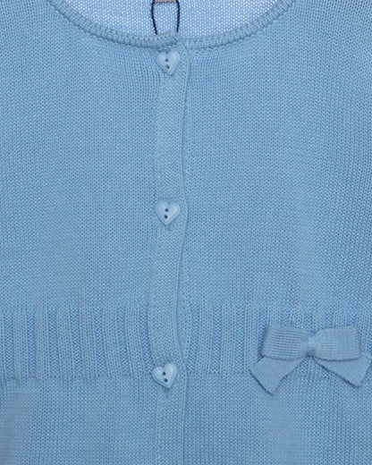 Close-up of a blue knitted cardigan with heart buttons and a bow detail.