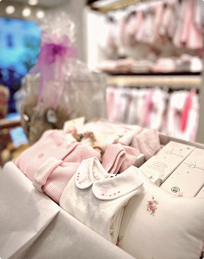 Children's clothing on display in a store with pink and white outfits.