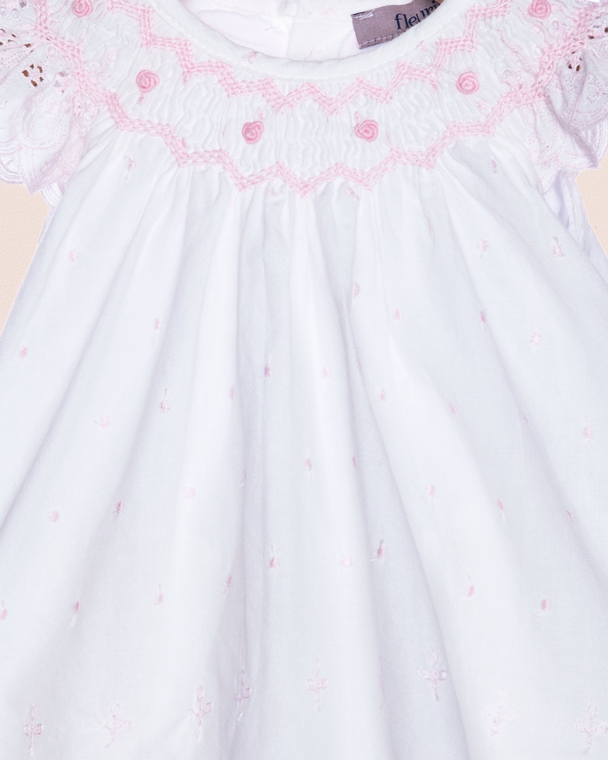 White dress with pink floral embroidery on a light background
