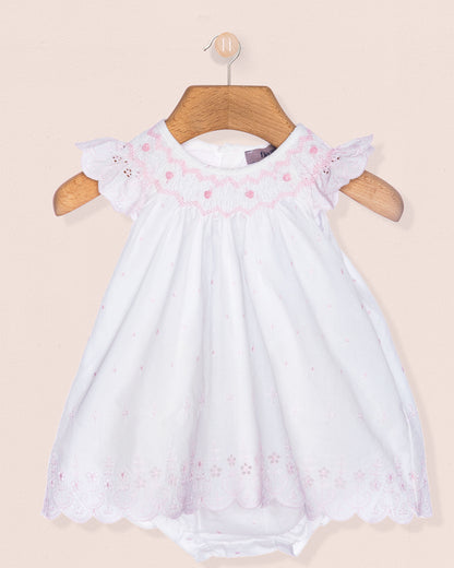 White baby dress with pink floral embroidery on a beige background