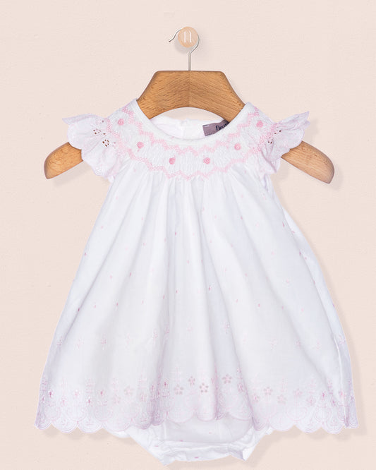 White baby dress with pink floral embroidery on a beige background
