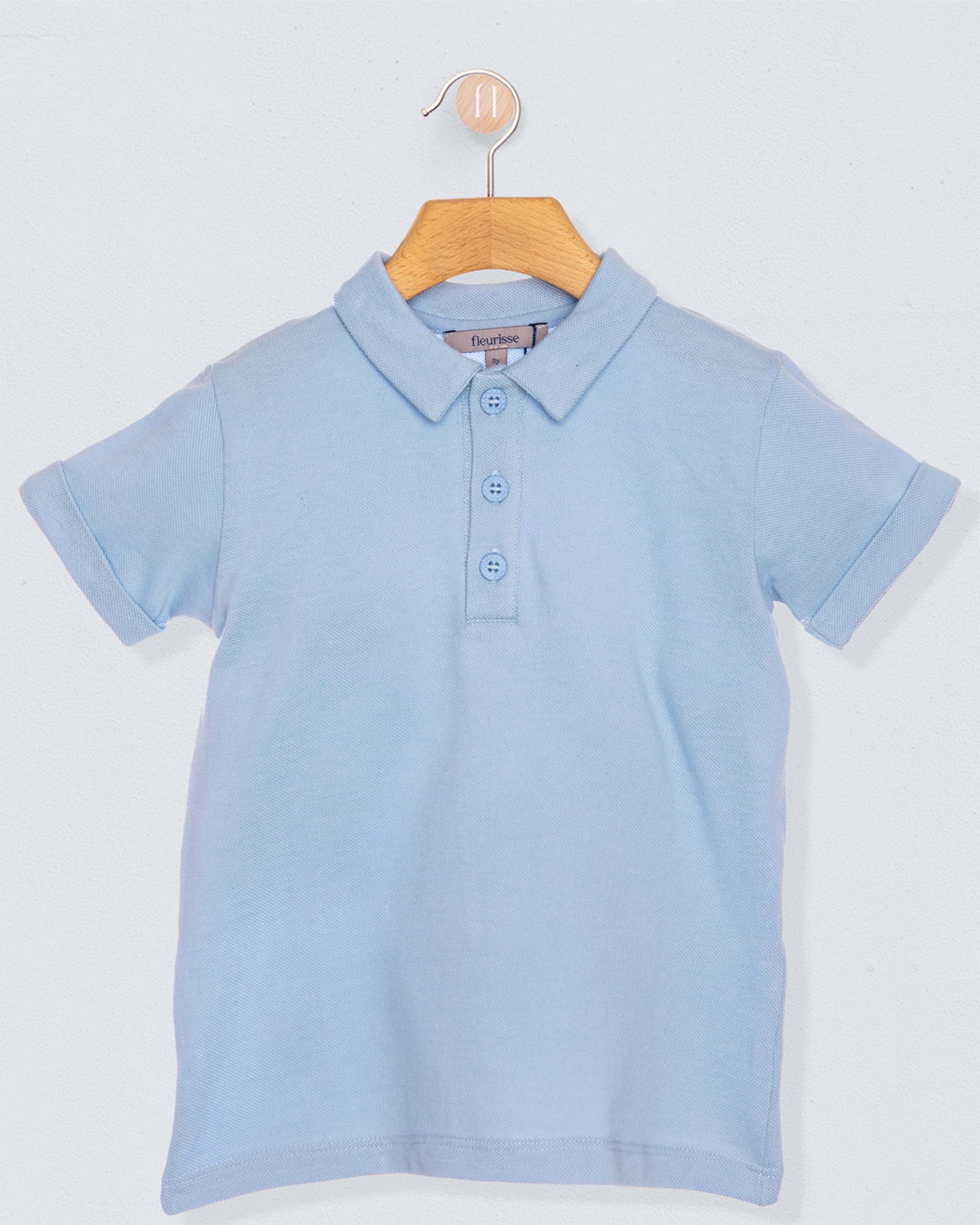 Light blue polo shirt on a wooden hanger against a light gray background