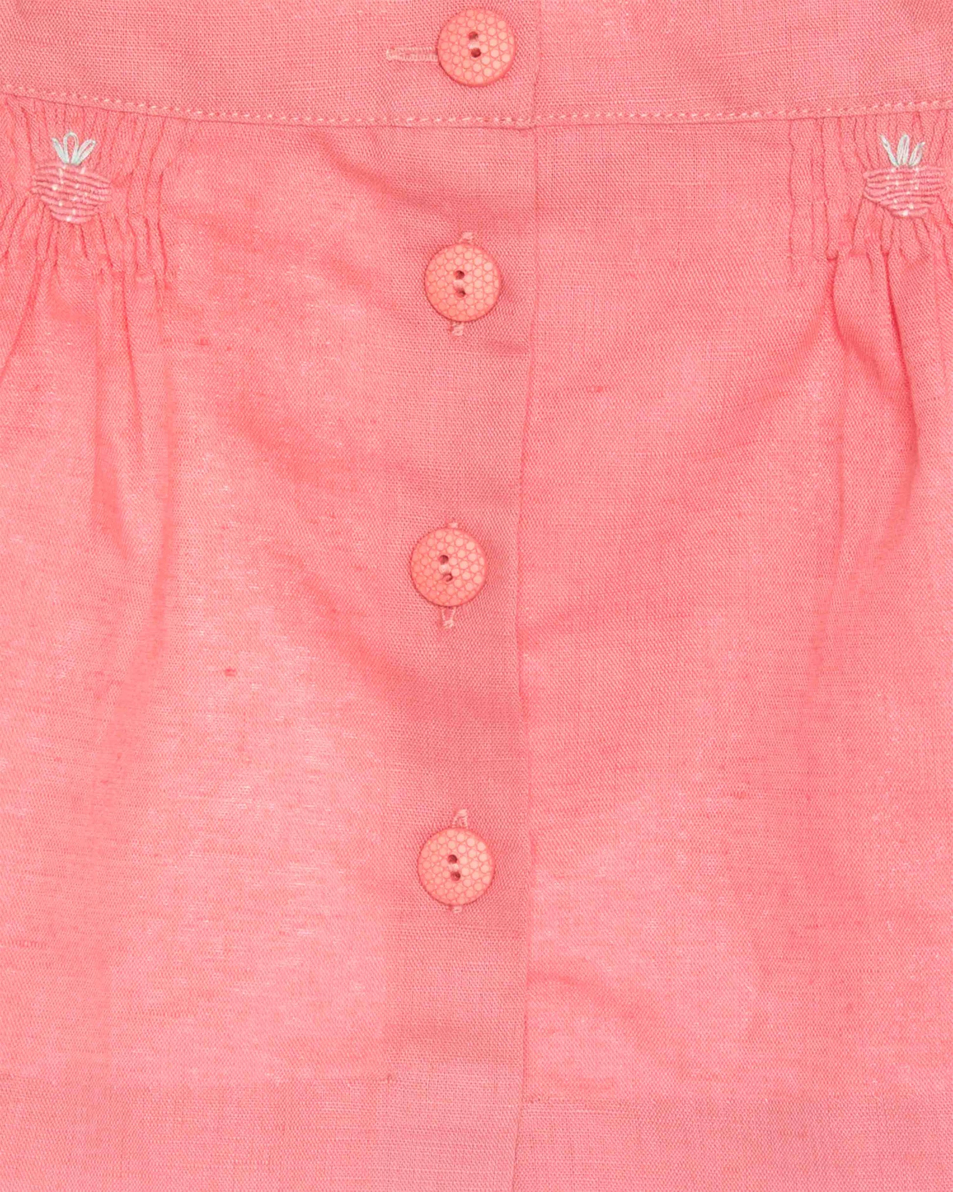 Close-up of a pink shirt with buttons and floral patterns on a light background