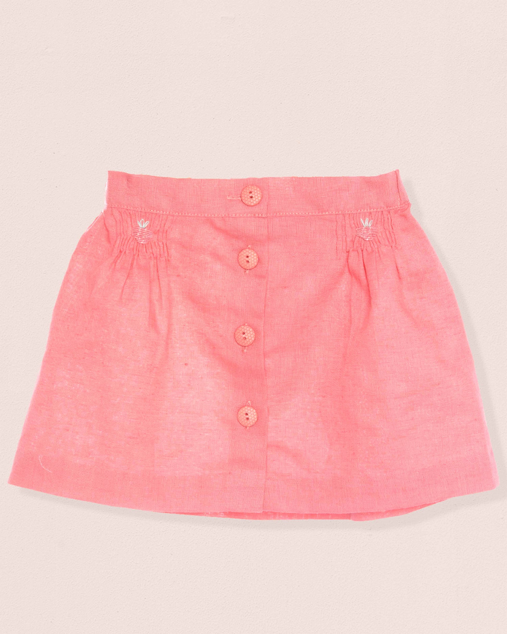 Pink skirt with button details on a light beige background