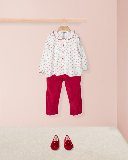 Children's outfit with floral shirt and red pants on a pink background