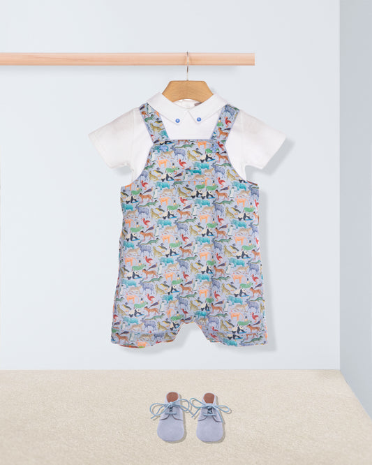 Baby outfit with patterned overalls, white shirt, and blue shoes on a light background