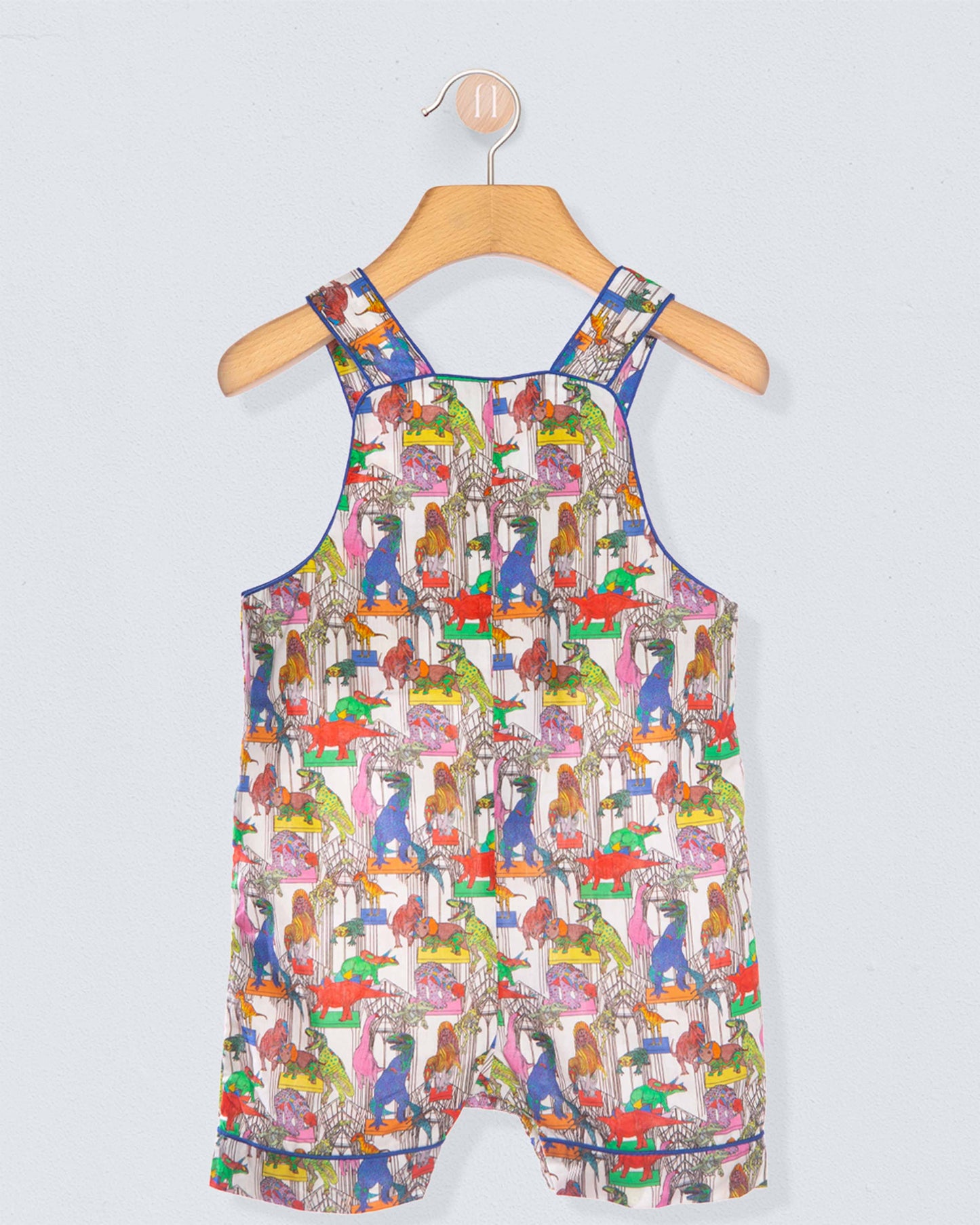 Colorful children's dress with animal pattern on a hanger against a light gray background