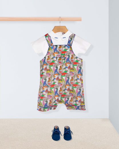 Colorful patterned overalls on a hanger with a white shirt underneath, on a light gray background.