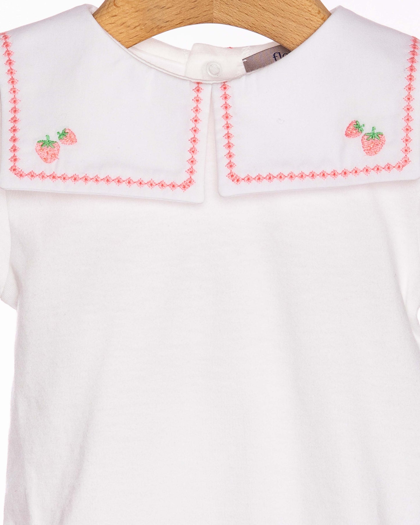White dress with red embroidery on a wooden hanger
