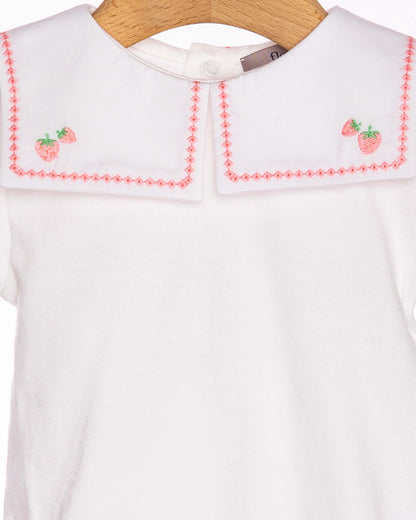 White dress with red embroidery on a wooden hanger