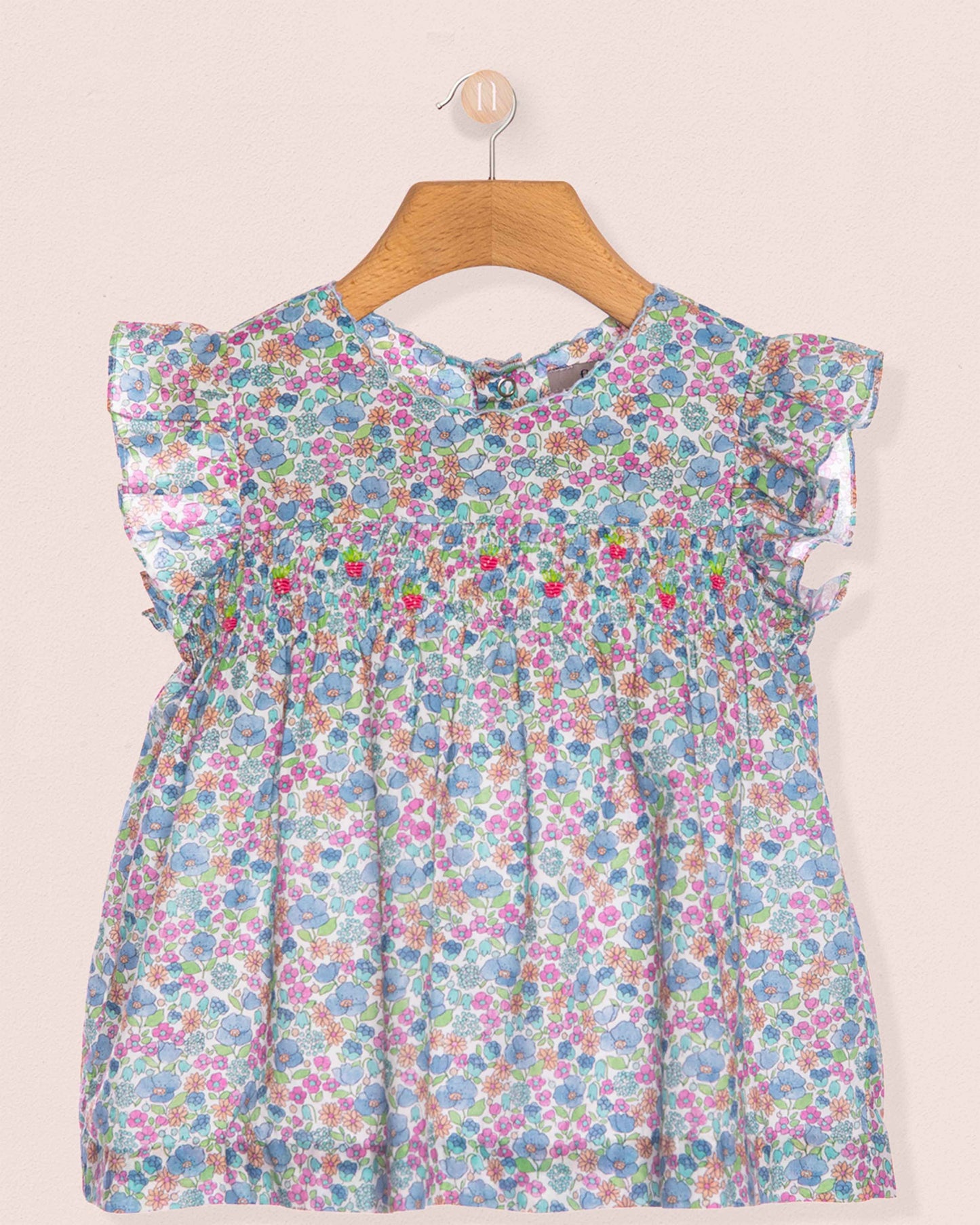 Floral dress on a hanger against a plain background