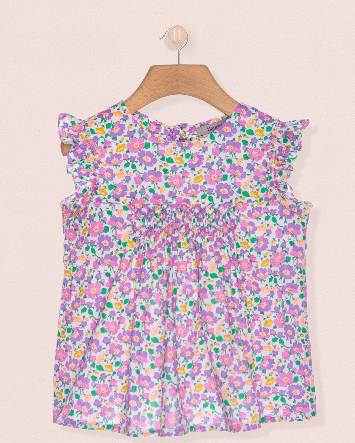 Floral dress on a hanger against a beige background
