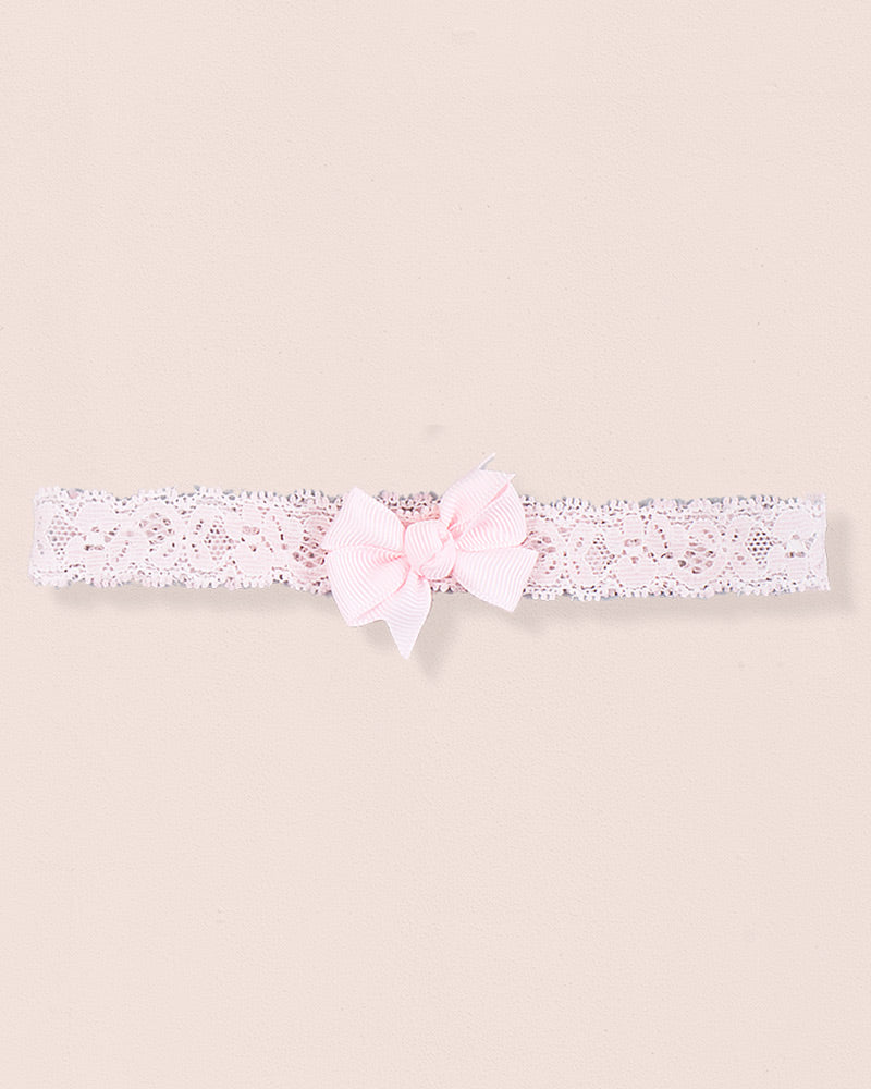 Pink baby headband made of lace with a centered grosgrain bow displayed on a neutral background