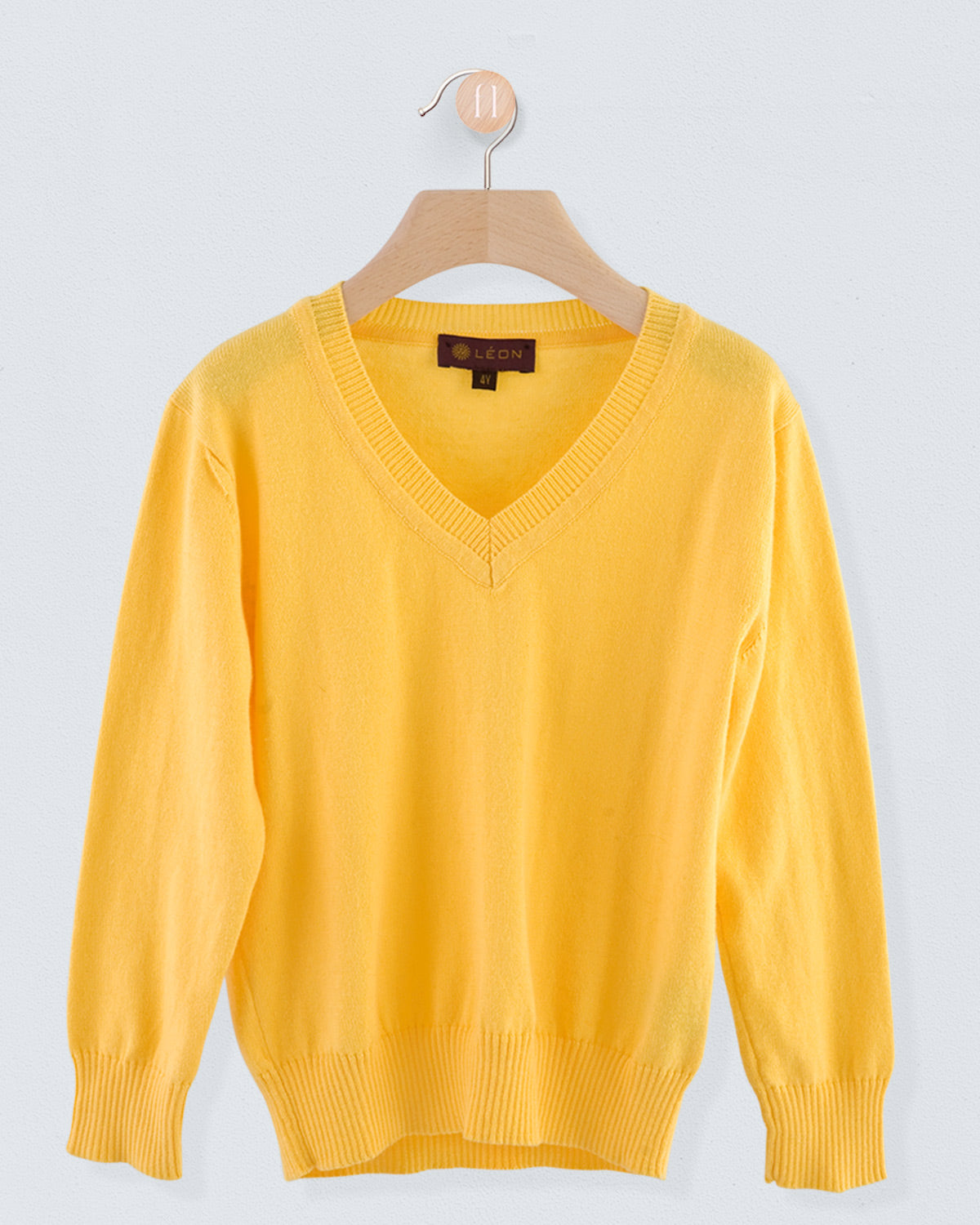ront view of the Arnaud Cotton Sweater in sunrise yellow with a V-neckline and ribbed cuffs and hem hanging on a wooden hanger