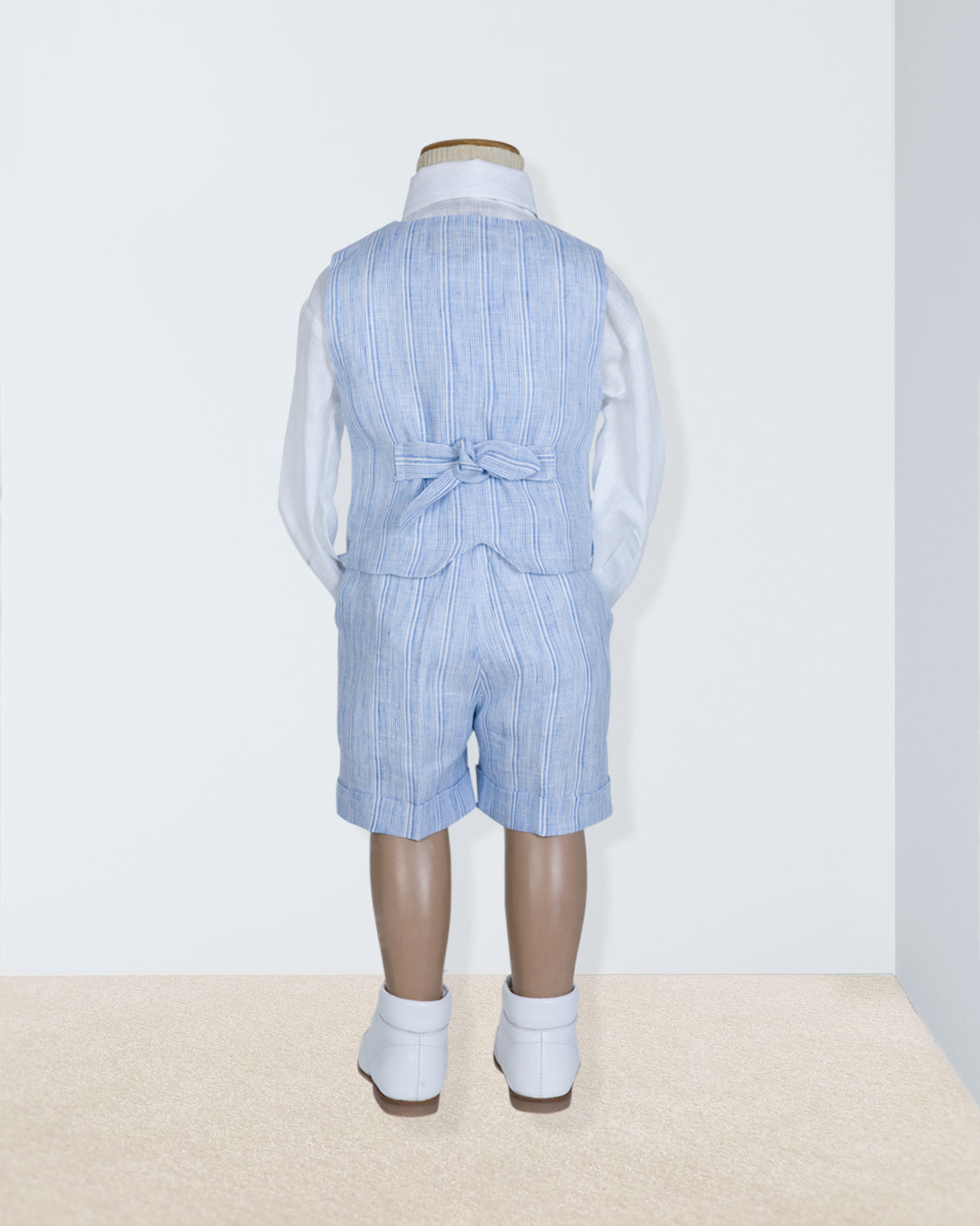 Back view of blue striped linen vest and suspender shorts with bow detail at the waist, shown on a child-sized mannequin