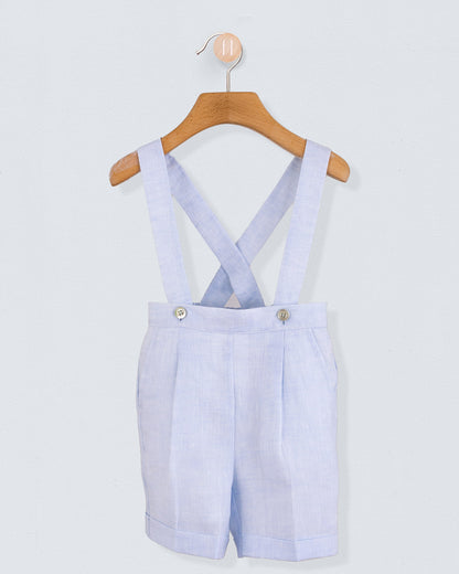 Front view of light blue linen suspender shorts with crossed straps buttoned at the waist, displayed on hanger.