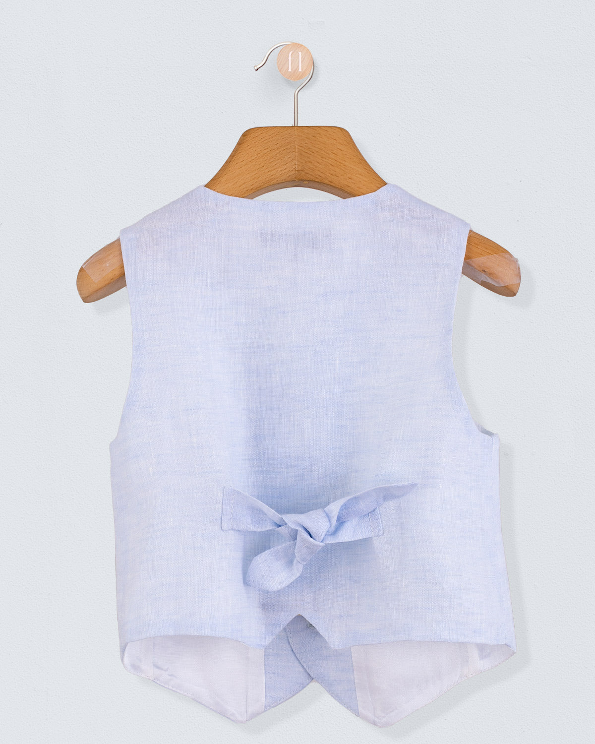 Back view of light blue linen vest with a decorative bow at the waist, shown on a hanger