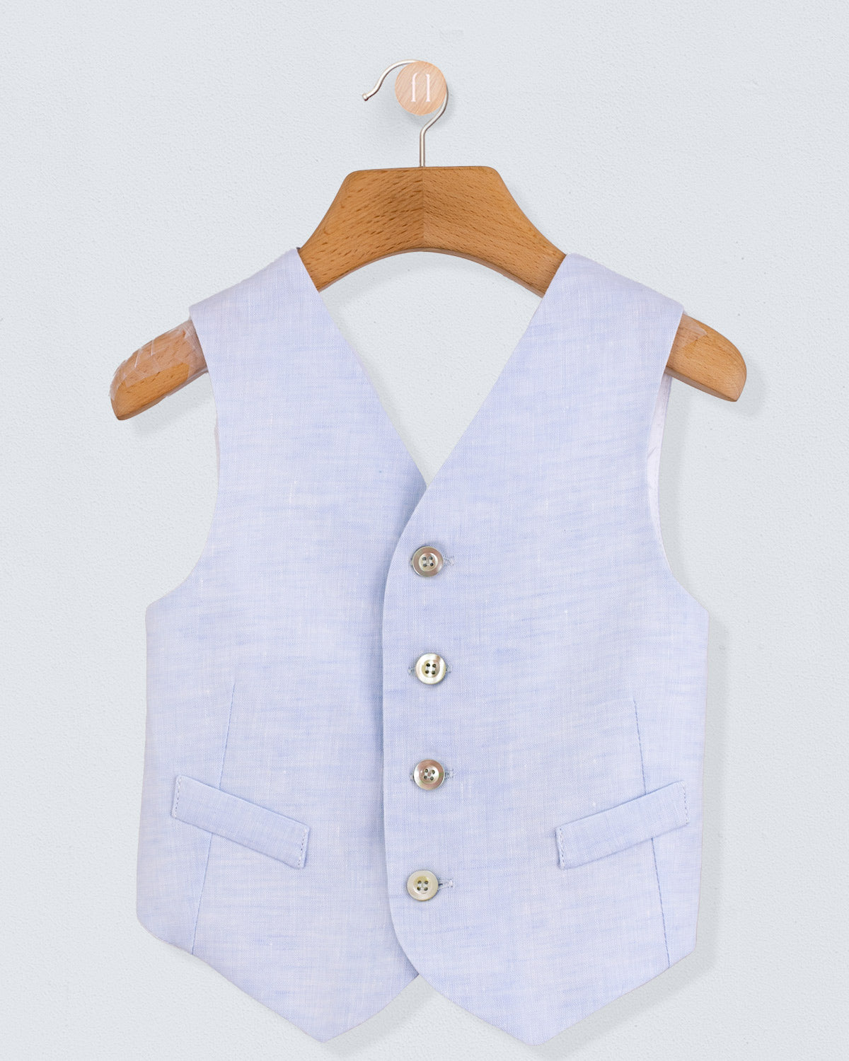 Front view of light blue linen vest with branded corozo buttons and front pockets, displayed on hanger