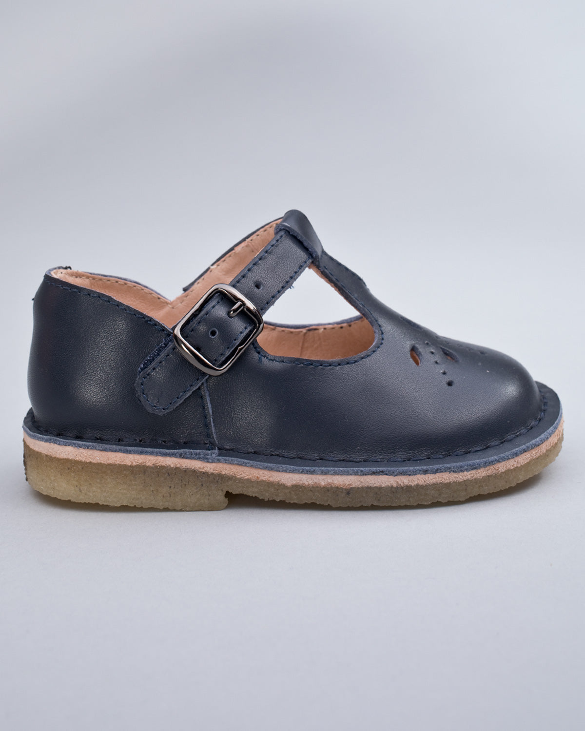 Side profile of a navy leather crepe sole toddler shoe with velcro strap and buckle detail