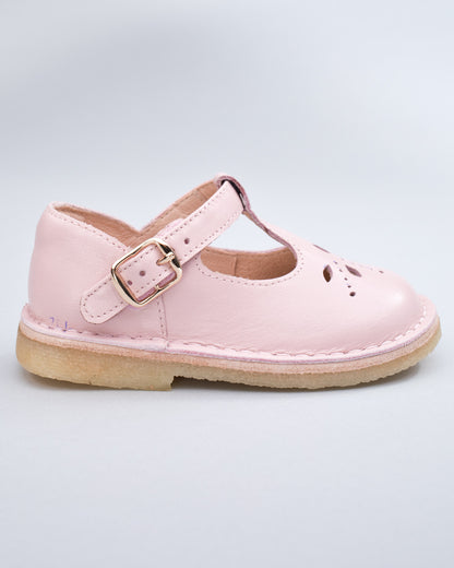 Side profile of a pink leather crepe sole toddler shoe with velcro strap and buckle detail