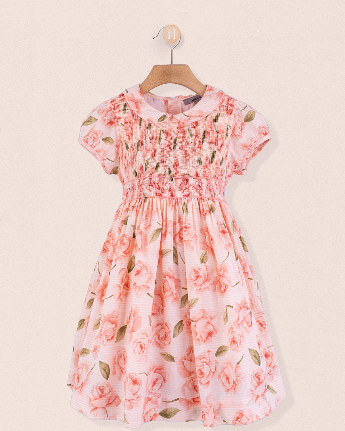 Front view of Amanda Bianca rose smock dress hanging on a wooden hanger