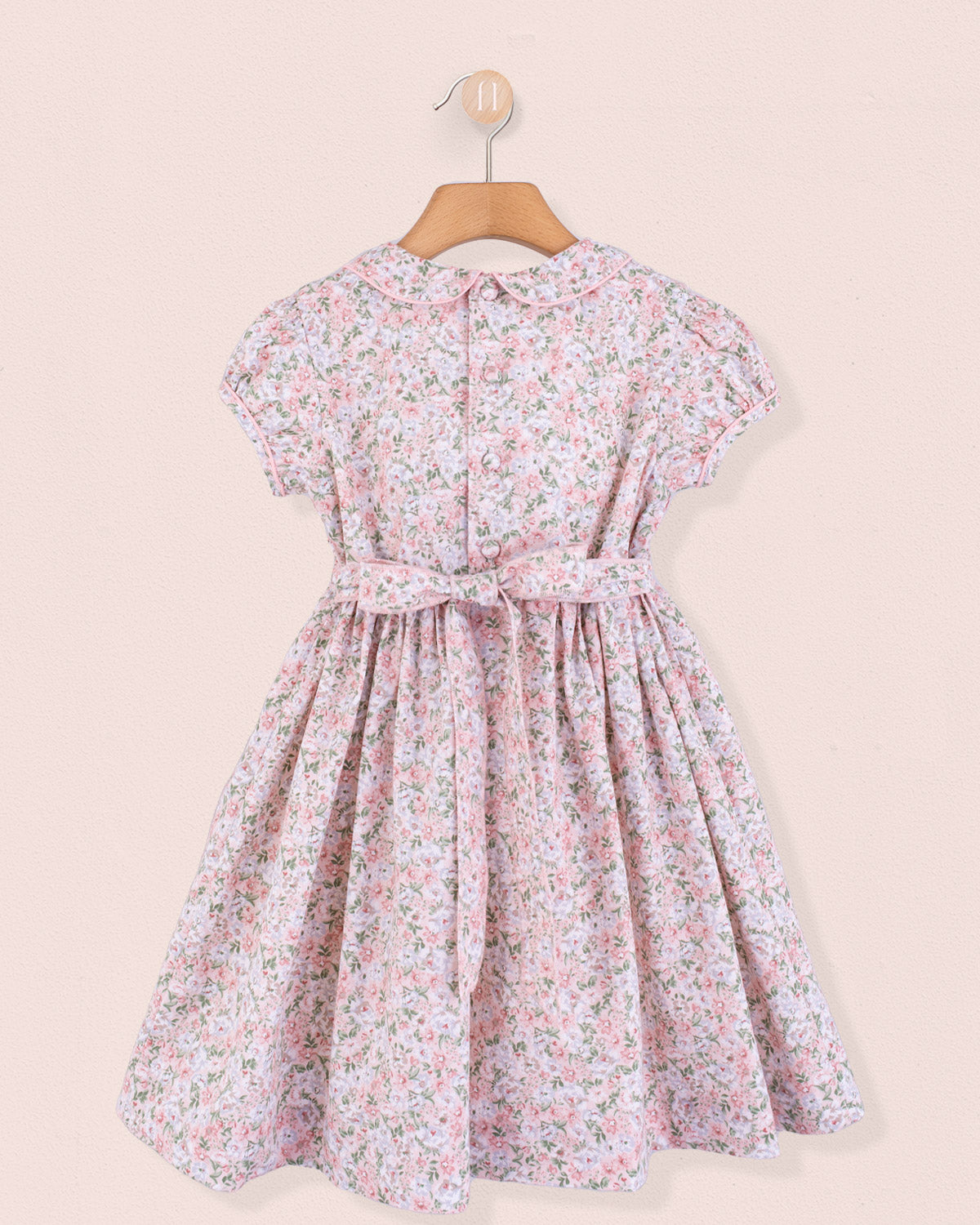 Back view of pink floral dress on hanger showing fabric sash