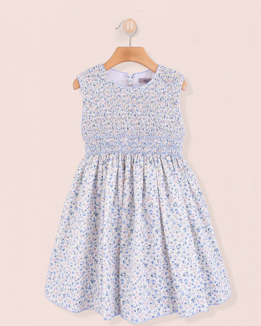 Front view of the Amandine Florencia Blue Floral Dress, a sleeveless, hand-smocked cotton dress with a round neckline and a gathered skirt in a light blue floral print.