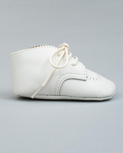 Side view of a single cream leather baby shoe with brogue stitching and lace-up closure.