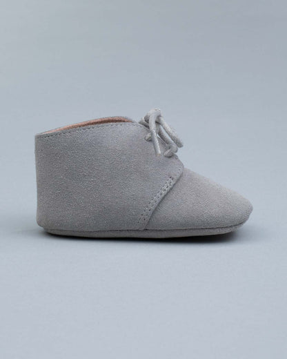 Side view of one grey suede crib shoes with tied laces.
