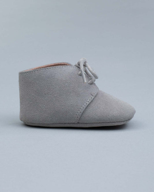 Side view of one grey suede crib shoes with tied laces.