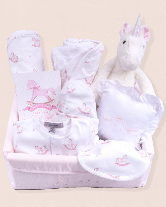pink/white baby girl gift basket featuring a unicorn stuffed animal greeting card, layette and bibs.