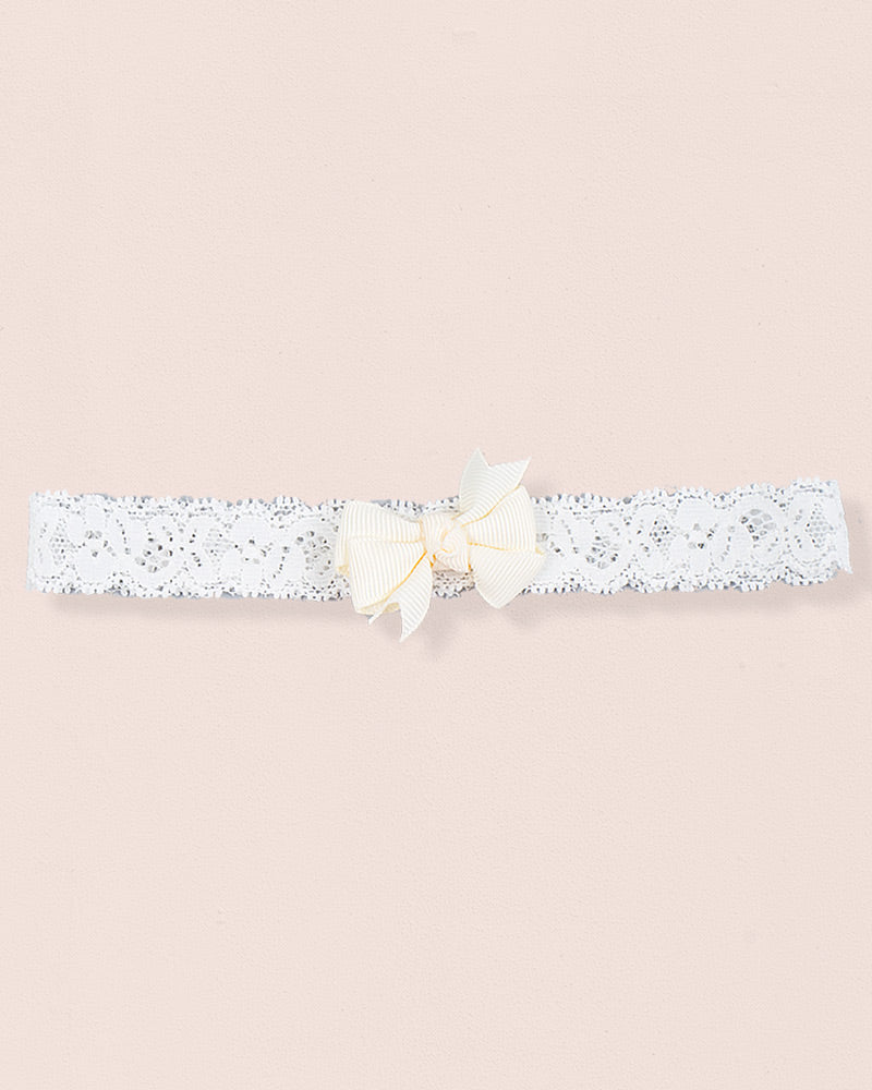 Cream baby headband made of lace with a centered grosgrain bow displayed on a neutral background
