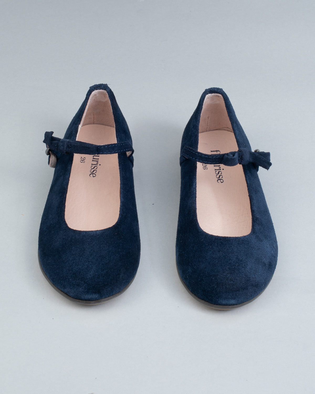Frontal view of navy suede Mary-Jane shoes for children, showcasing symmetrical bows and rounded toes on a flat background.