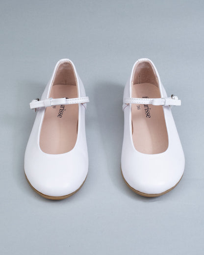 Frontal view of white leather Mary-Jane shoes for children, showcasing symmetrical bows and rounded toes on a flat background.