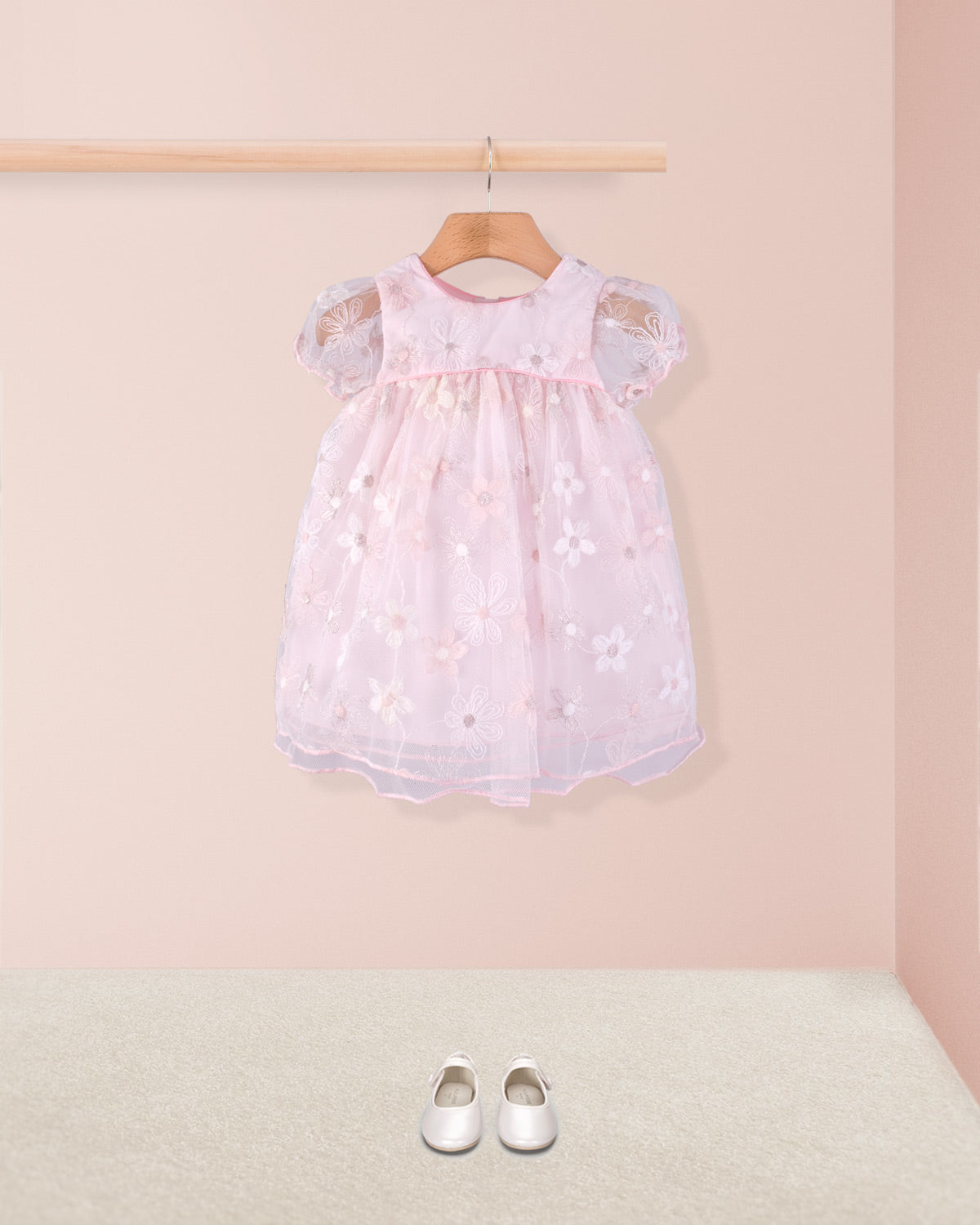 Full front view of Baby Isodora pink Tulle Dress styled with cream baby shoes on beige carpet and soft pink wall background.