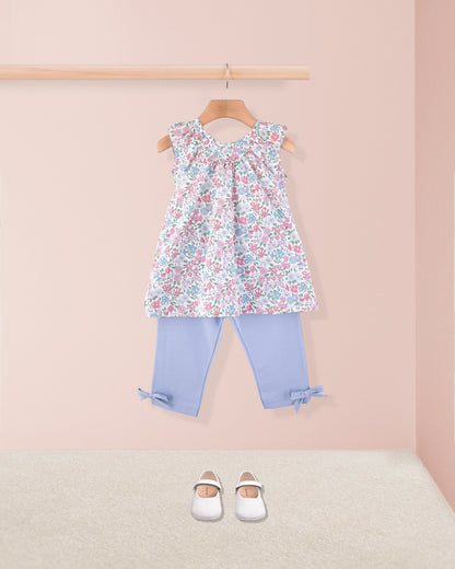 Alicia pastel tunic styled with light blue capri leggings and white shoes, hanging on a wooden hanger against a neutral backdrop