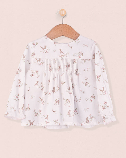 Long sleeve white tunic with pink deer and floral print, pin-tuck details on chest, hanging on wooden hanger