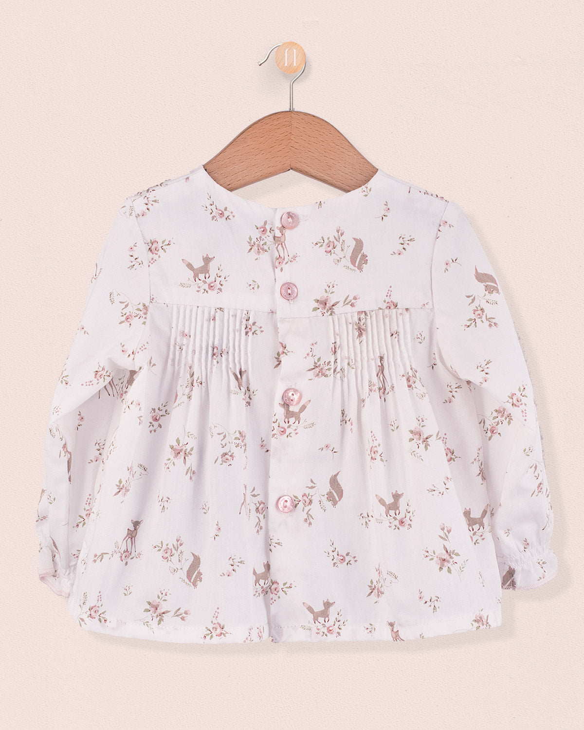 Back view of white tunic with pink deer and floral print, showing fabric-covered buttons and pleats