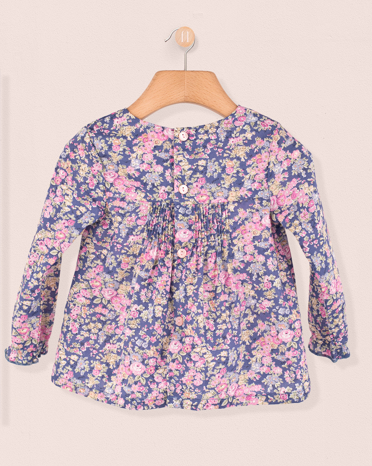 Back view of baby tunic in Liberty Tatum Blue floral cotton with dyed-to-match buttons and gathered detailing.