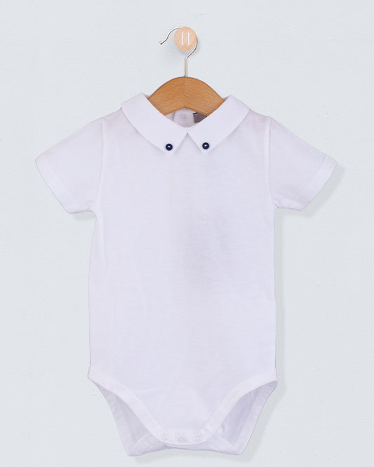 Front view of the Andreas White Onesie with Hunter Buttons, a short-sleeve white cotton jersey onesie with a crisp collar detailed with two small navy buttons.