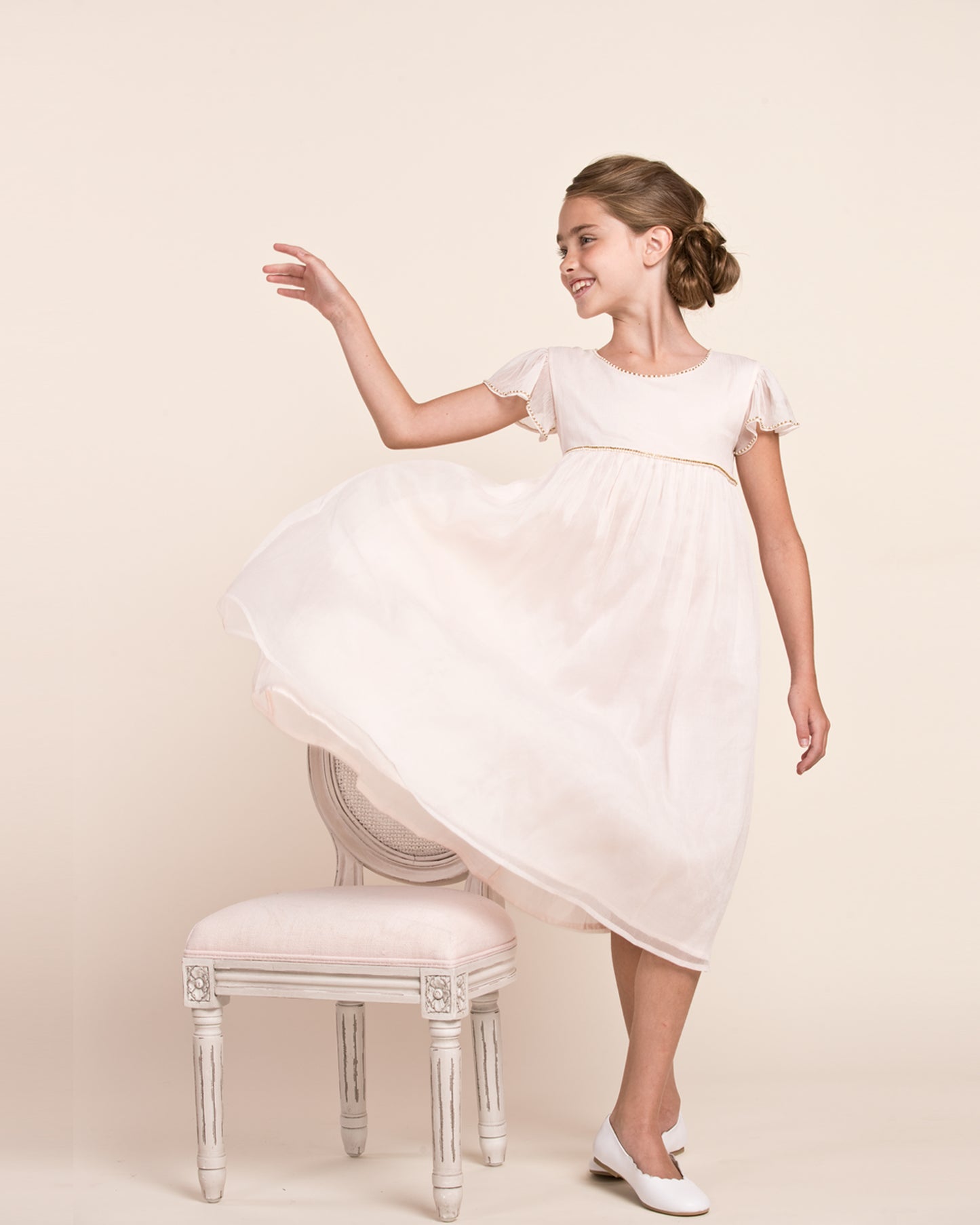 Girl turned to the front, looking to the side wearing Ophelia Cream Tulle Dress showing the front of the dress 