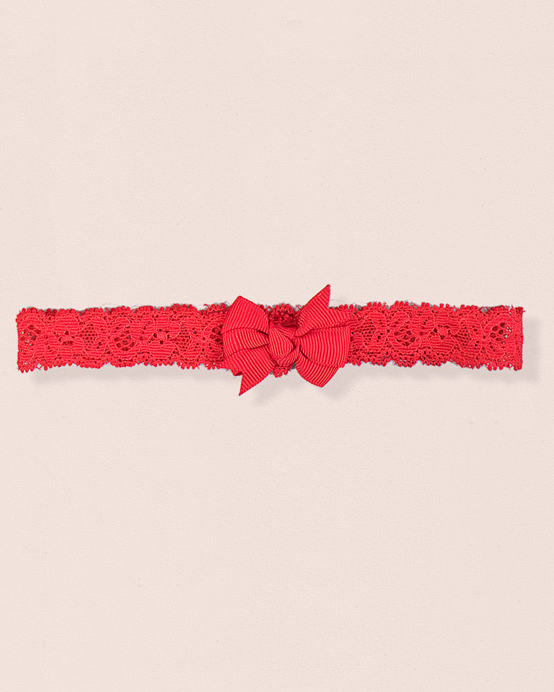 Red baby headband made of lace with a centered grosgrain bow displayed on a neutral background